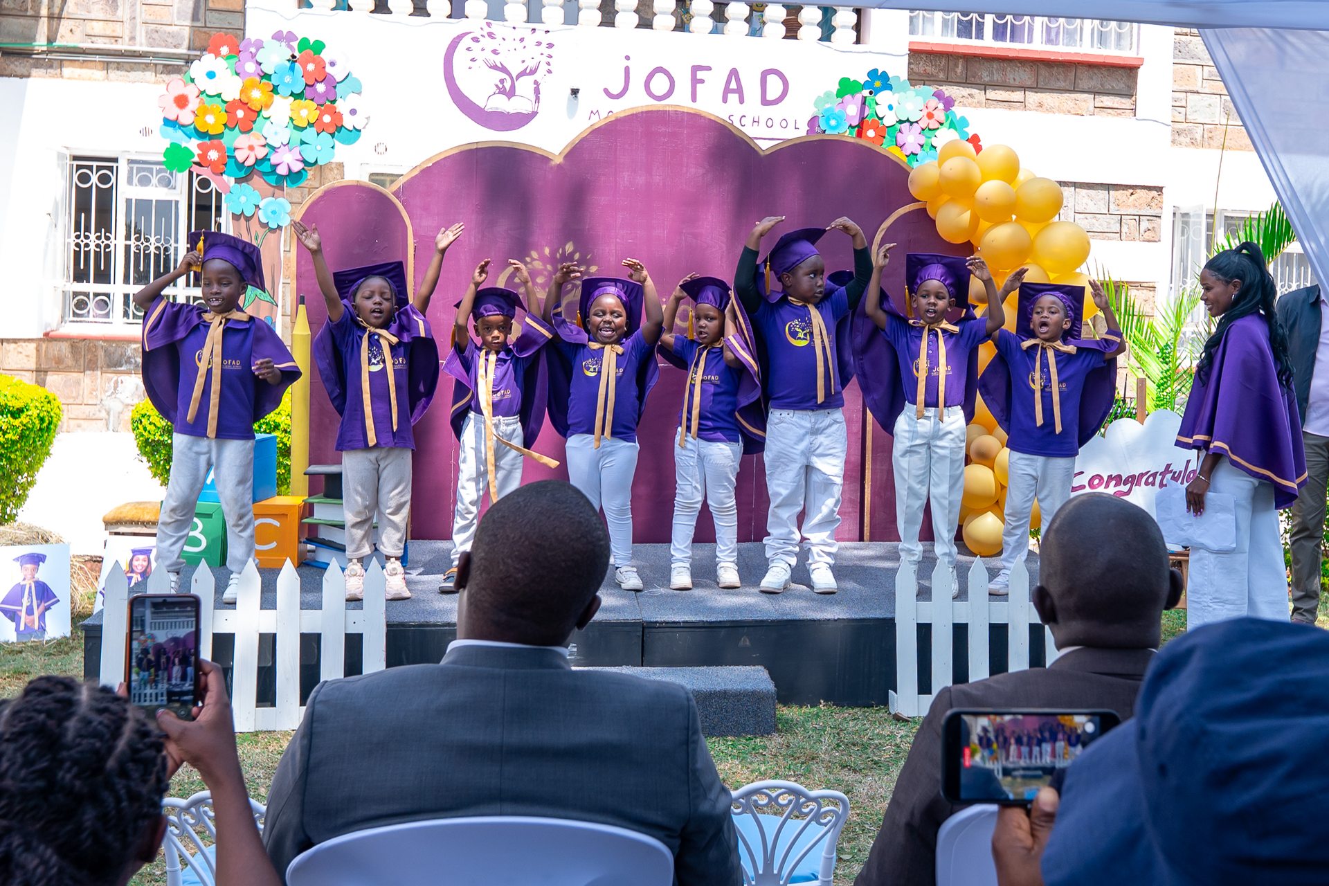 Children in graduation gowns performing on stage