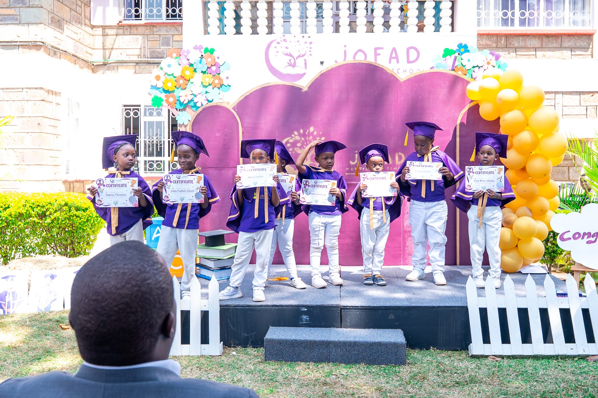 Jofad graduates with families and teachers holding certificates at ceremony