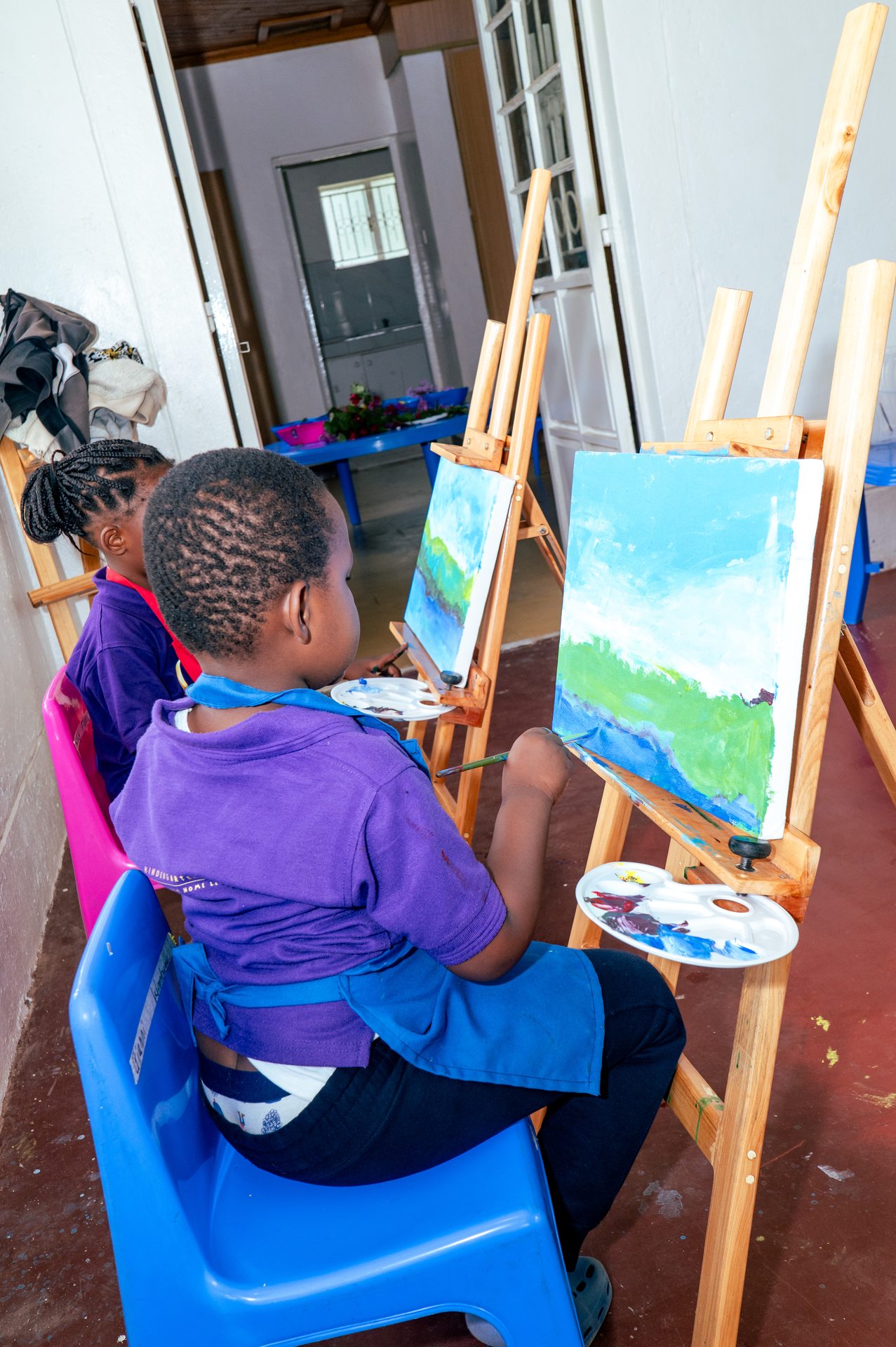 Children painting on easels in art class